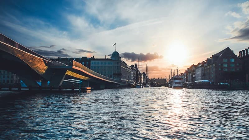 Wasserkanal mit Brücke und Gebäuden in Kopenhagen bei Sonnenuntergang, Standort der Baaderbank Banking Services.